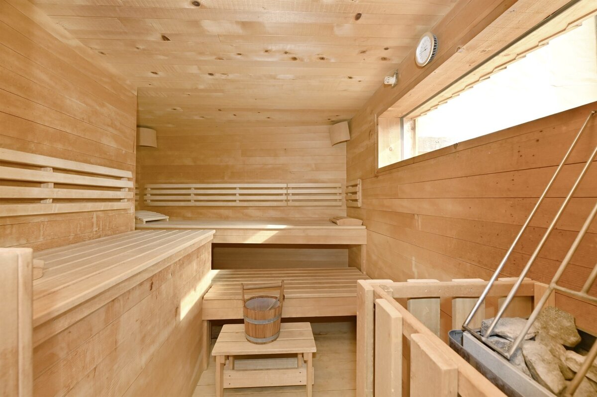 Helle Sauna aus Naturholz mit Ofen und Aufgusskübel