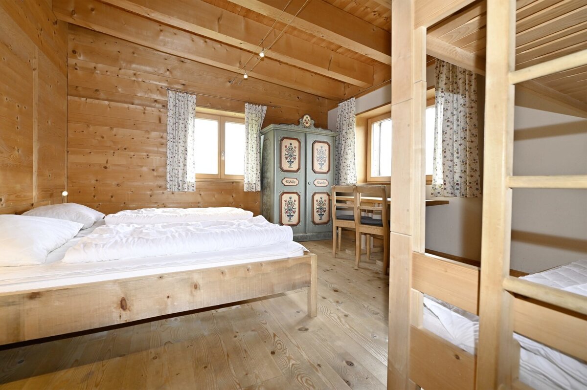 Schlafzimmer im Biohuus mit Doppelbett, Stockbett und bemaltem Bauernschrank