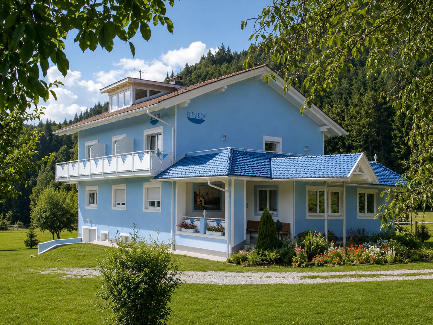 Die hellblaue Pension Lipusch mit Garten und Spielplatz