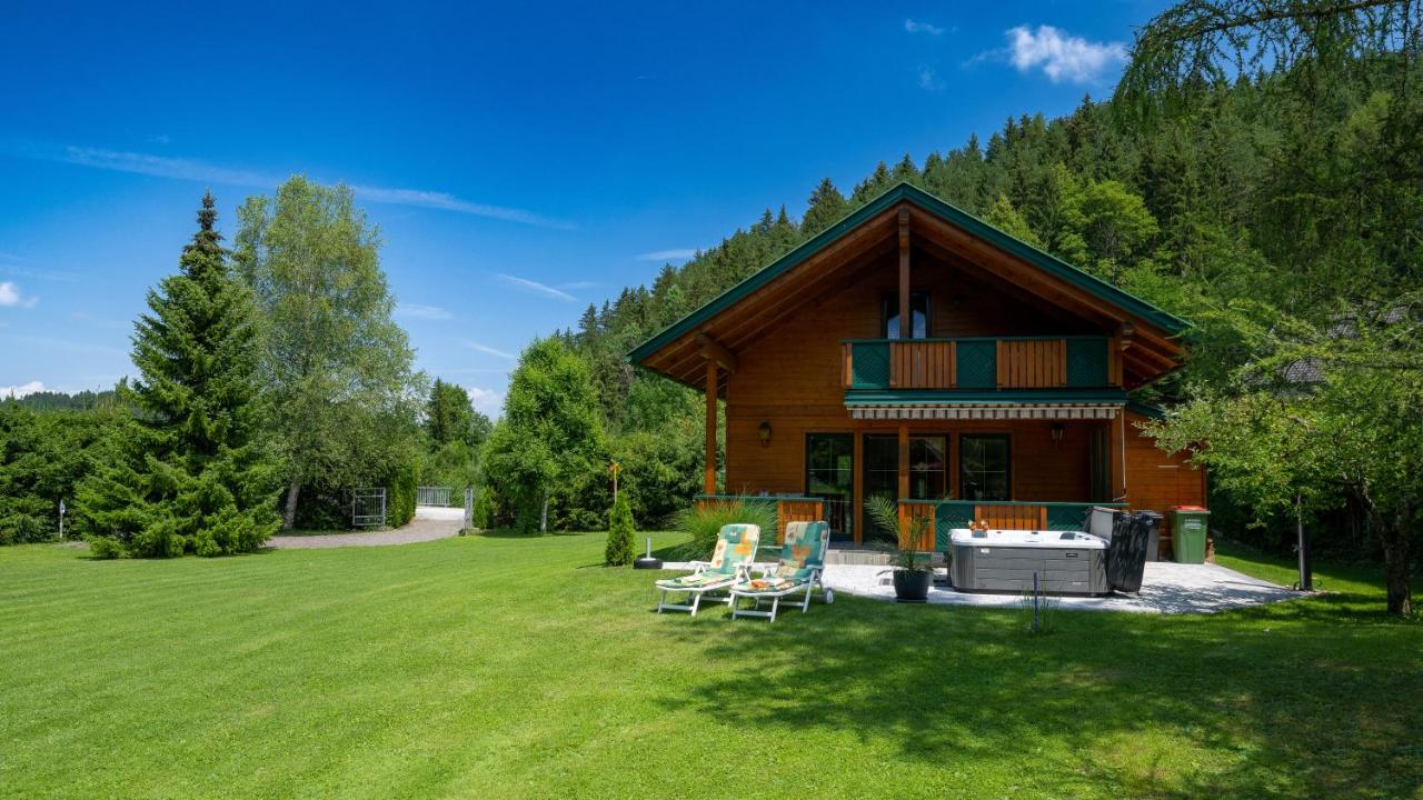 Das Ferienhaus an einem Sommertag mit Whirlpool und Liegestühlen im Garten