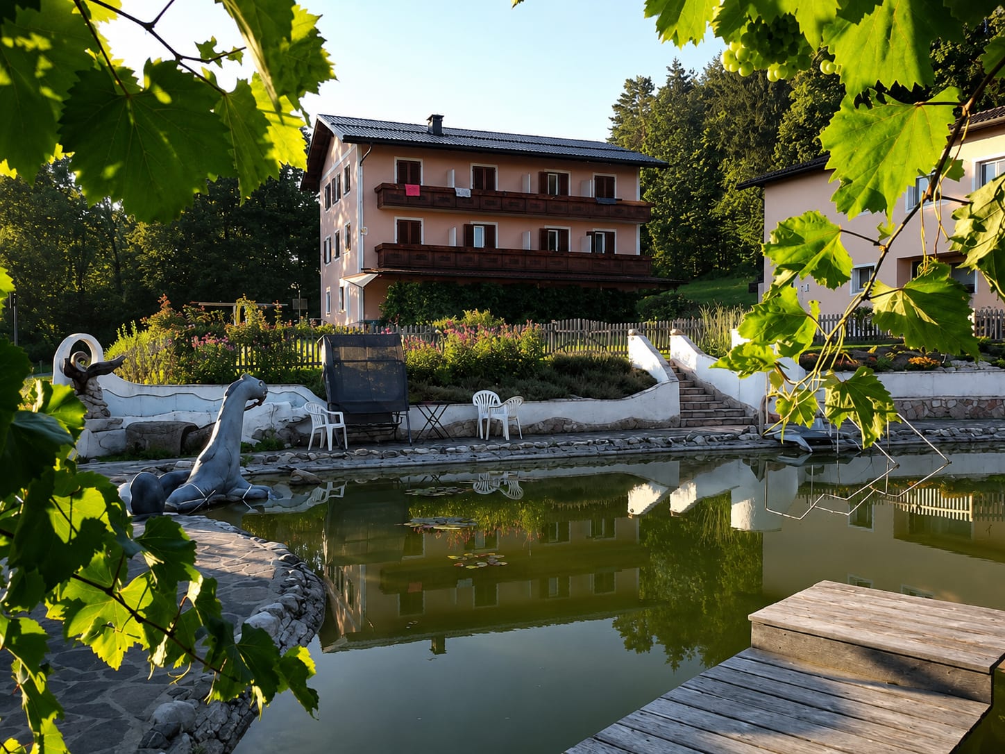 Das Gästehaus Georgibergl hinter dem hauseigenen Schwimmteich, gerahmt von Weinlaub