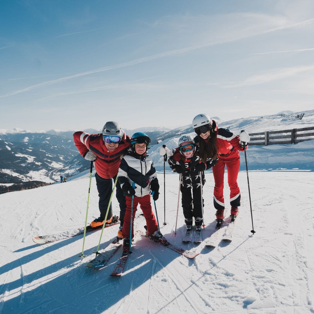 Familie auf Skiern auf der sonnigen Piste über dem Tal