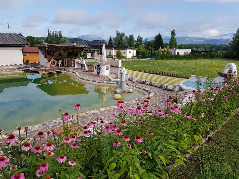 Hauseigener Schwimmteich mit schattiger Laube und blühenden Stauden