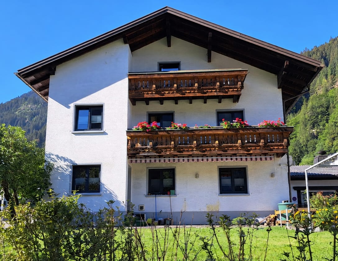 Haus von Peter Mathies in Gortipohl mit Blumenbalkonen und Bergkulisse