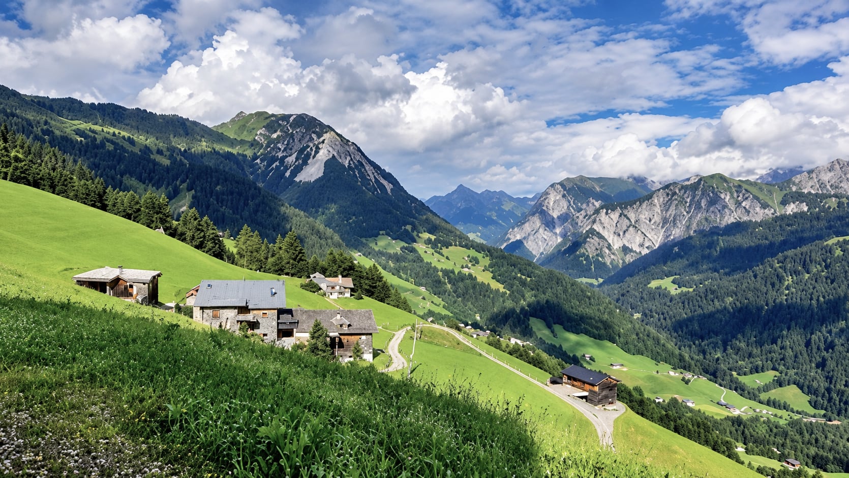 Bauernhöfe auf der Bergwiese über dem Großen Walsertal mit Blick auf die Gipfel